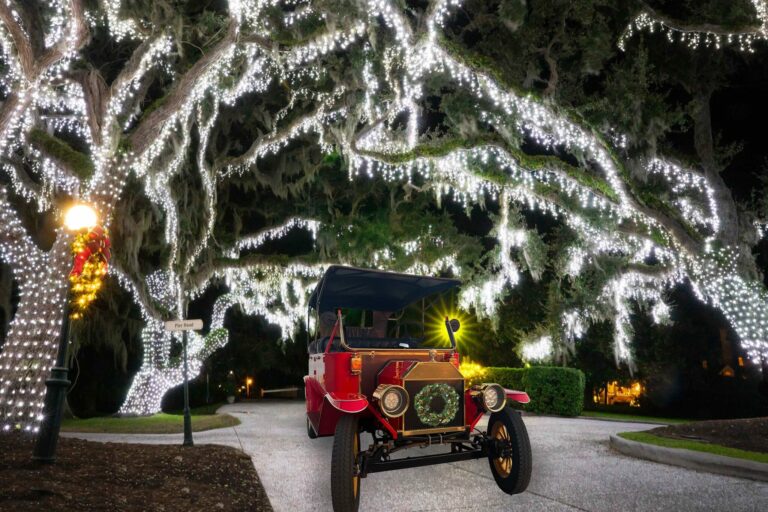 Old-fashioned motorcar under the live oak trees wrapped in holiday lights for Holly Jolly Jekyll.